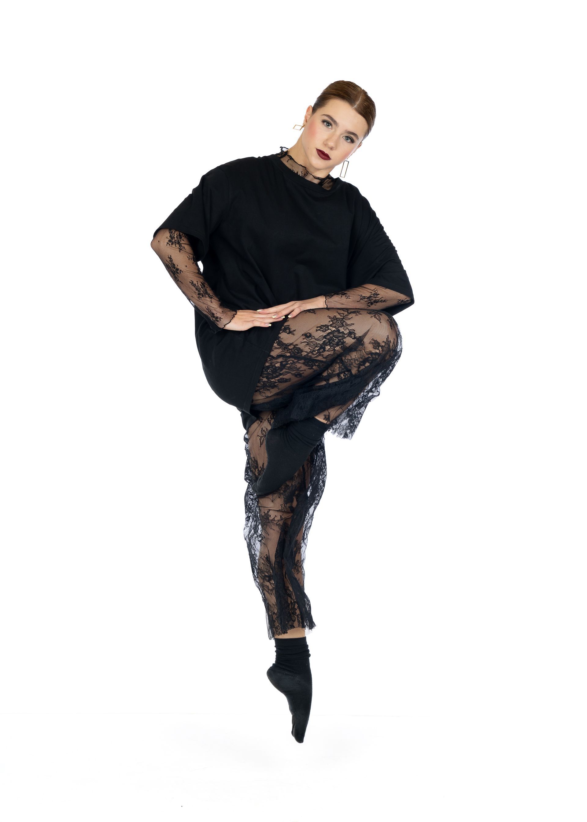 Person posing in black outfit with lace pants and top against a white background.
