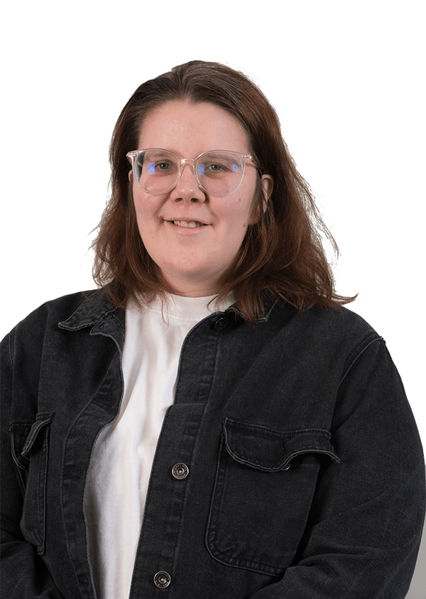 A woman wearing glasses and a black jacket is smiling for the camera.