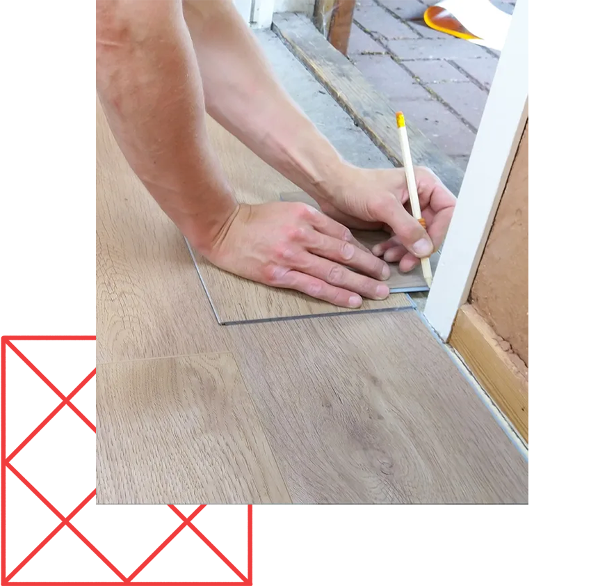 A person is measuring a piece of wood with a pencil