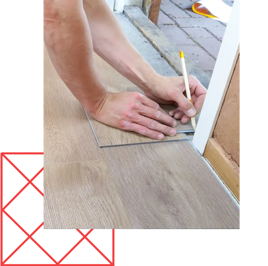 A person is measuring a piece of wood with a pencil