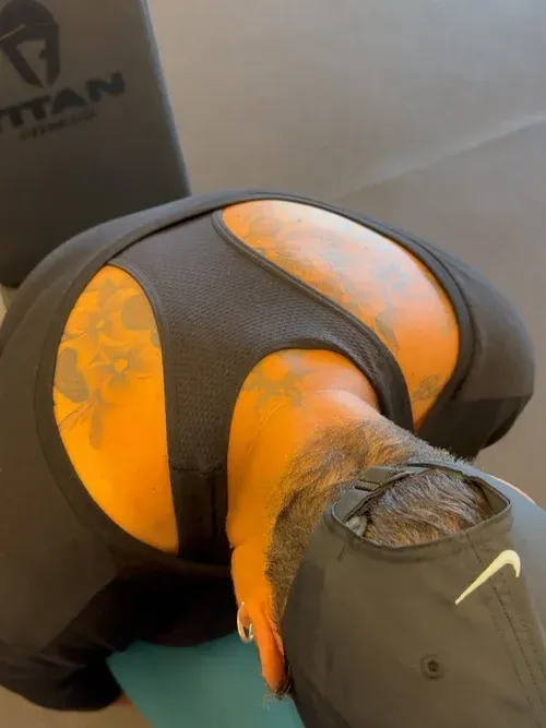 Person bent over on a gym mat, wearing black shorts and a gray cap.