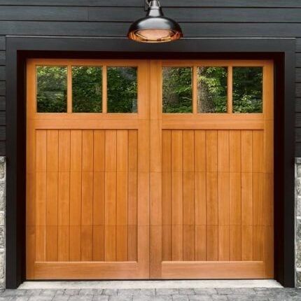 Wooden garage door with four small windows beneath a dark exterior light