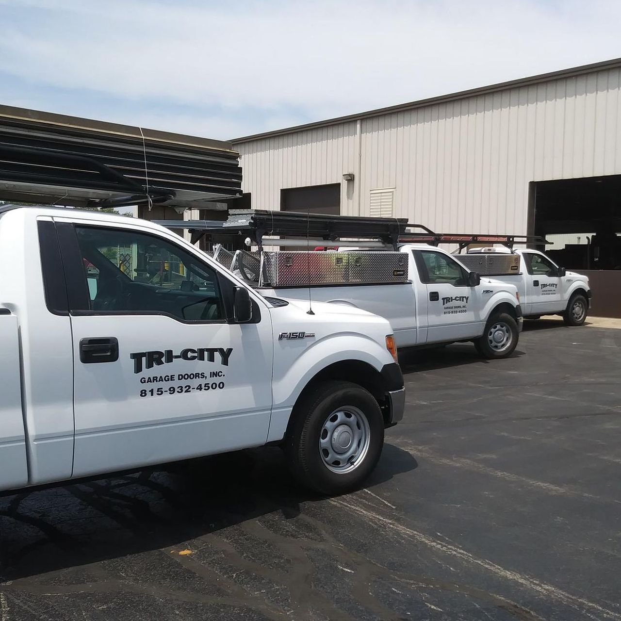 White Tri-City service trucks parked outside a warehouse loading area