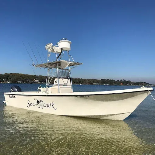 White fishing boat named Sea Hawk on calm water under a clear blue sky.