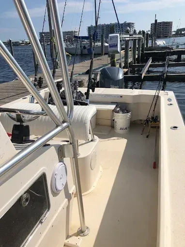 Boat deck with railings, white bucket, and marina docked boats in the background