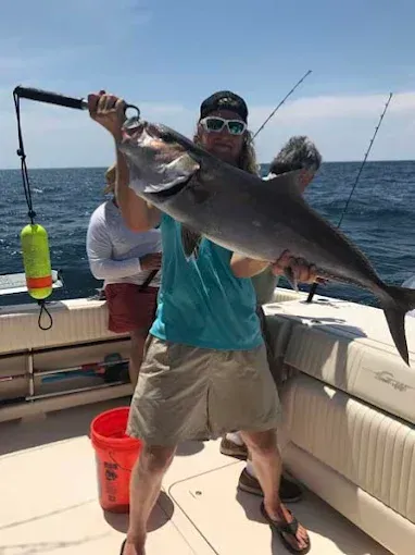 Person on a boat holding a large fish while fishing on open water