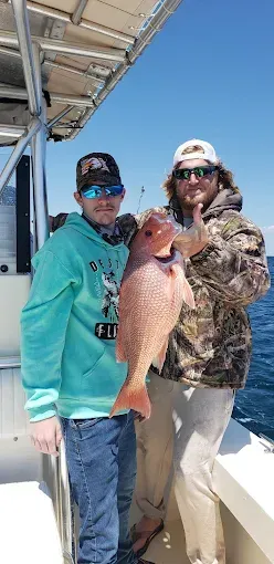 Two people on a boat holding a large fish under a bright blue sky
