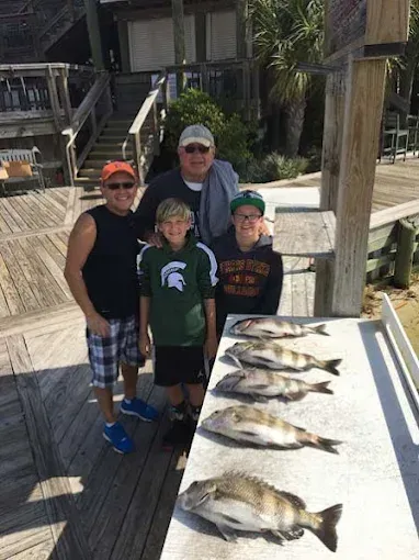 Family posing beside a table of fresh fish on a dock by the water