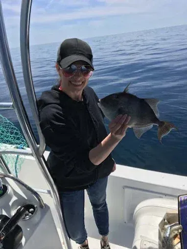 Person on a boat holding a large fish on the open ocean