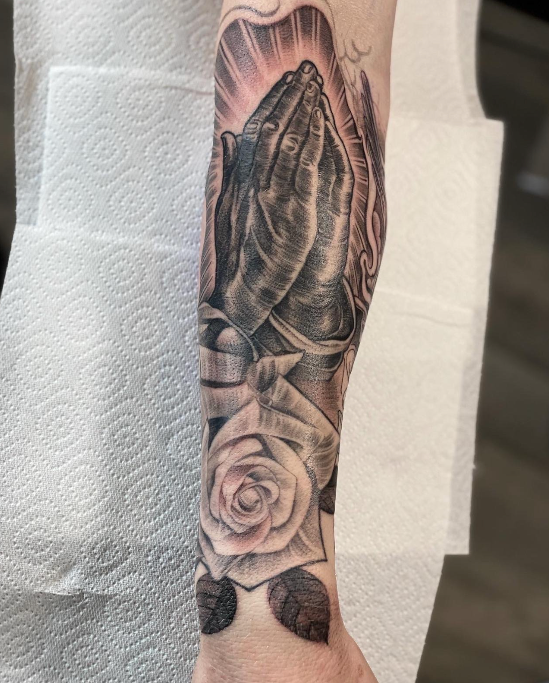 Black-and-gray floral tattoo sleeve with a rose and large leaves on an arm