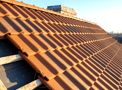 Orange clay roof tiles on a sloped rooftop under bright sunlight