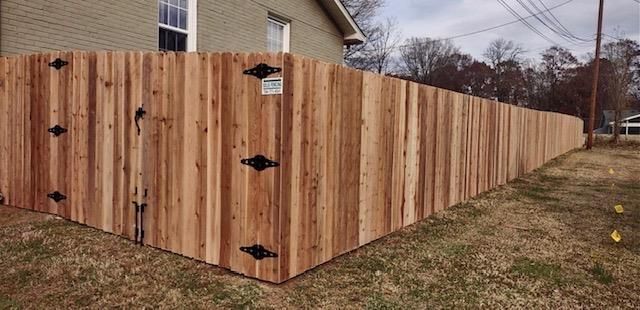 A wooden fence with a gate is in front of a house.