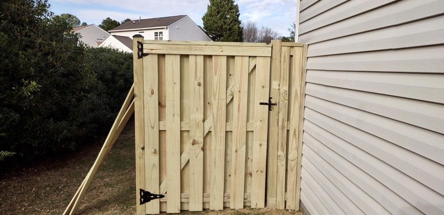 A wooden fence is sitting next to a white house.