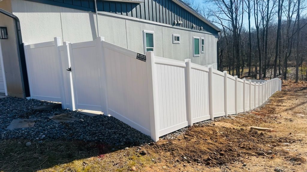 A black fence surrounds a driveway in a backyard.