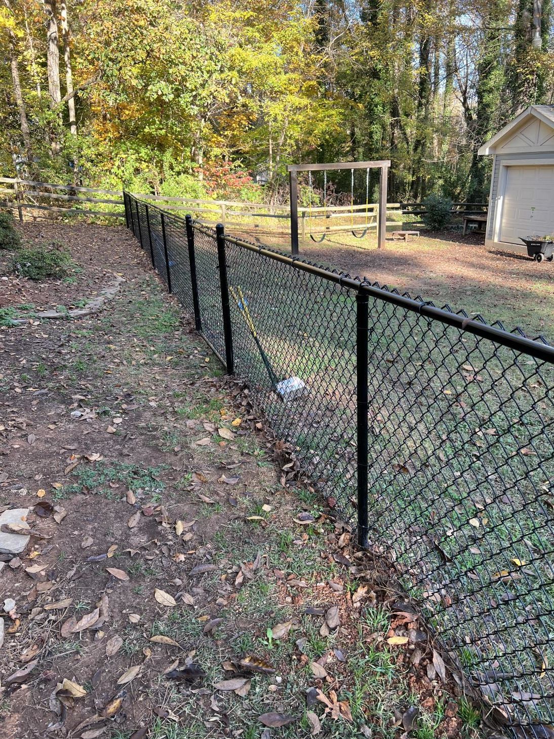 A chain link fence surrounds a yard with a playground in the background.