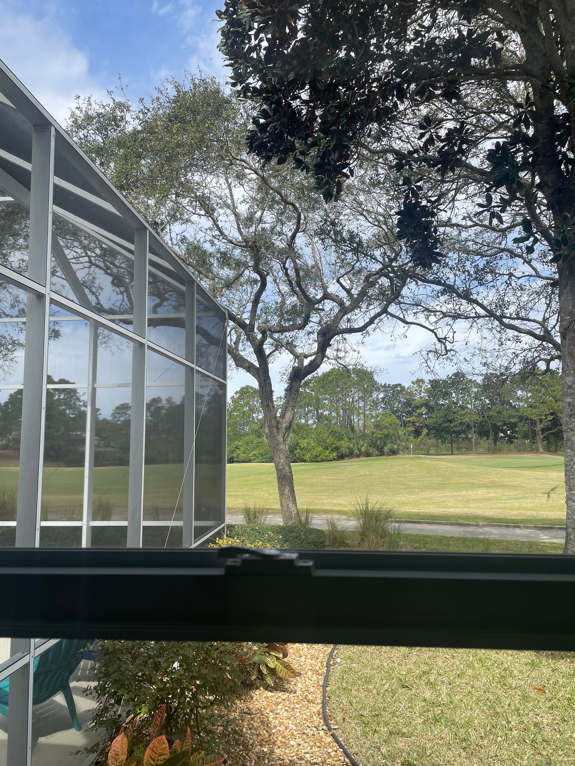 A screened in porch with a view of a golf course.