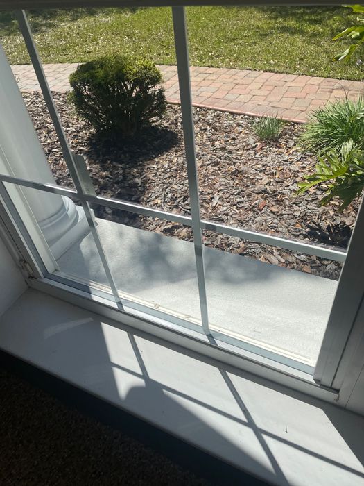 A window with a brick walkway in the background