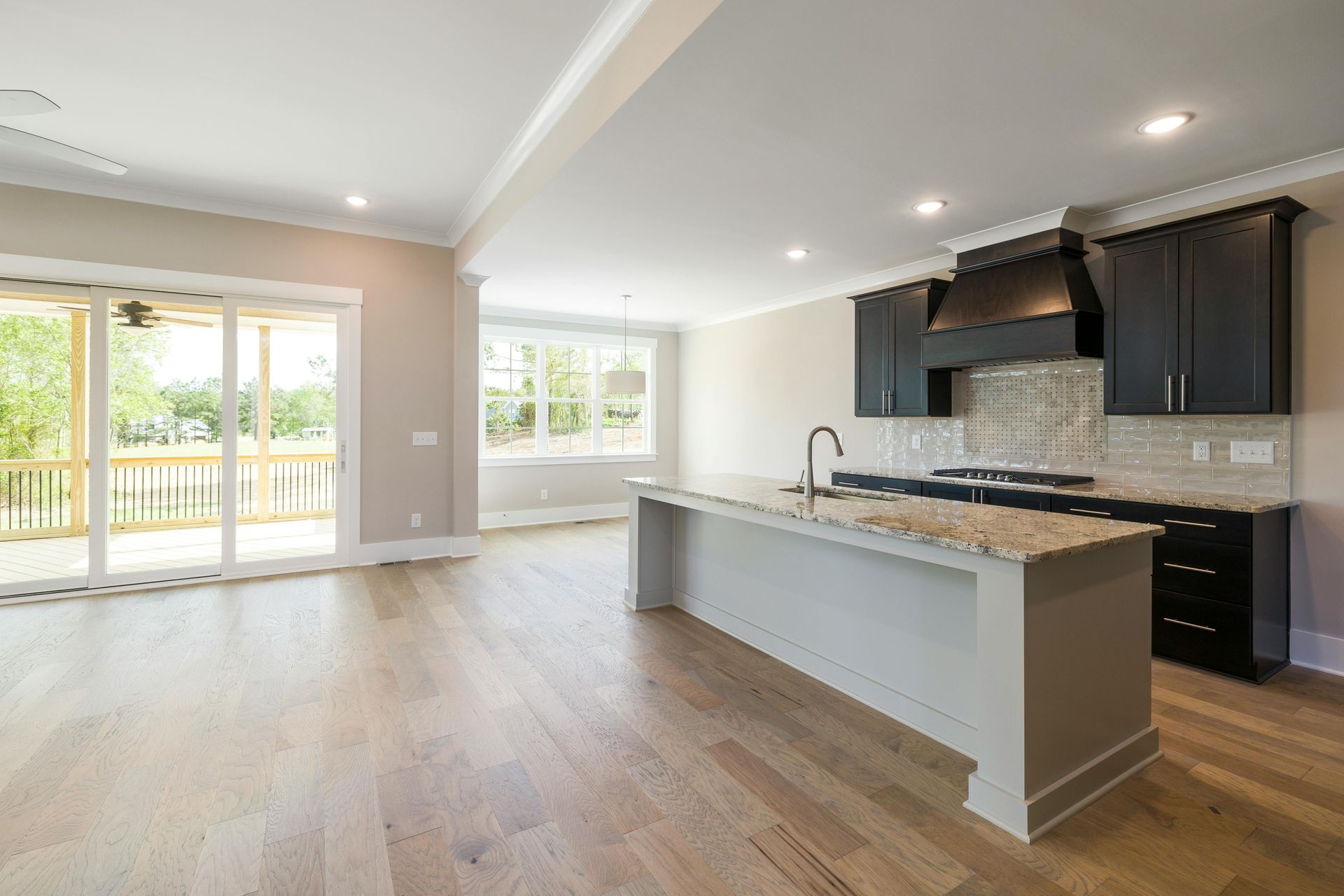 Modern kitchen with island, dark cabinets, stainless appliances, and light wood flooring.