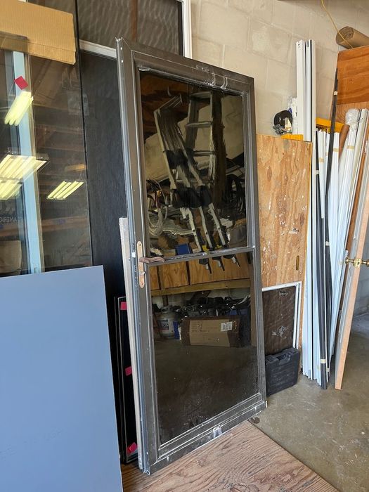 A large mirror is sitting on a wooden floor in a garage.