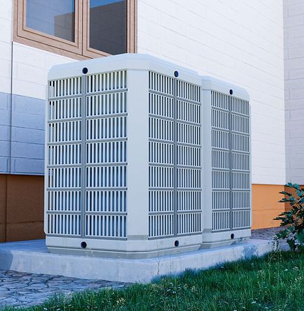 Deux unités de climatisation blanches à l'extérieur d'un bâtiment.