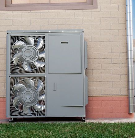 Unité de pompe à chaleur fixée sur un mur de briques avec deux ventilateurs. Métal gris et gazon vert.