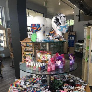 Display of face masks and beauty products in a store with mannequins wearing masks, on a glass-topped table.
