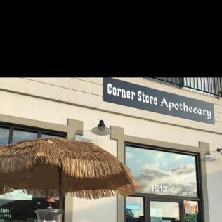 Corner Store Apothecary storefront with thatch umbrella. Sign reads 