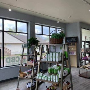 Interior of a store selling CBD products. Shelves display products, plants, and signage in a bright setting.