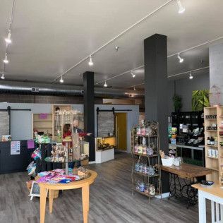 Interior of a shop with displays of products, gray columns, and a wooden floor.