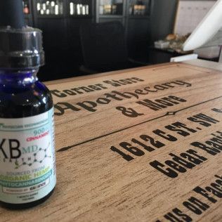 A CBD tincture bottle on a wooden sign for an apothecary in Cedar Rapids, Iowa.