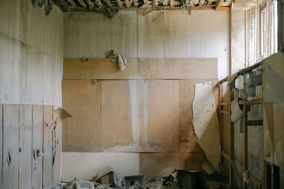 Professional painter in white overalls painting an interior wall white.