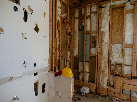 Professional painter in white overalls painting an interior wall white.