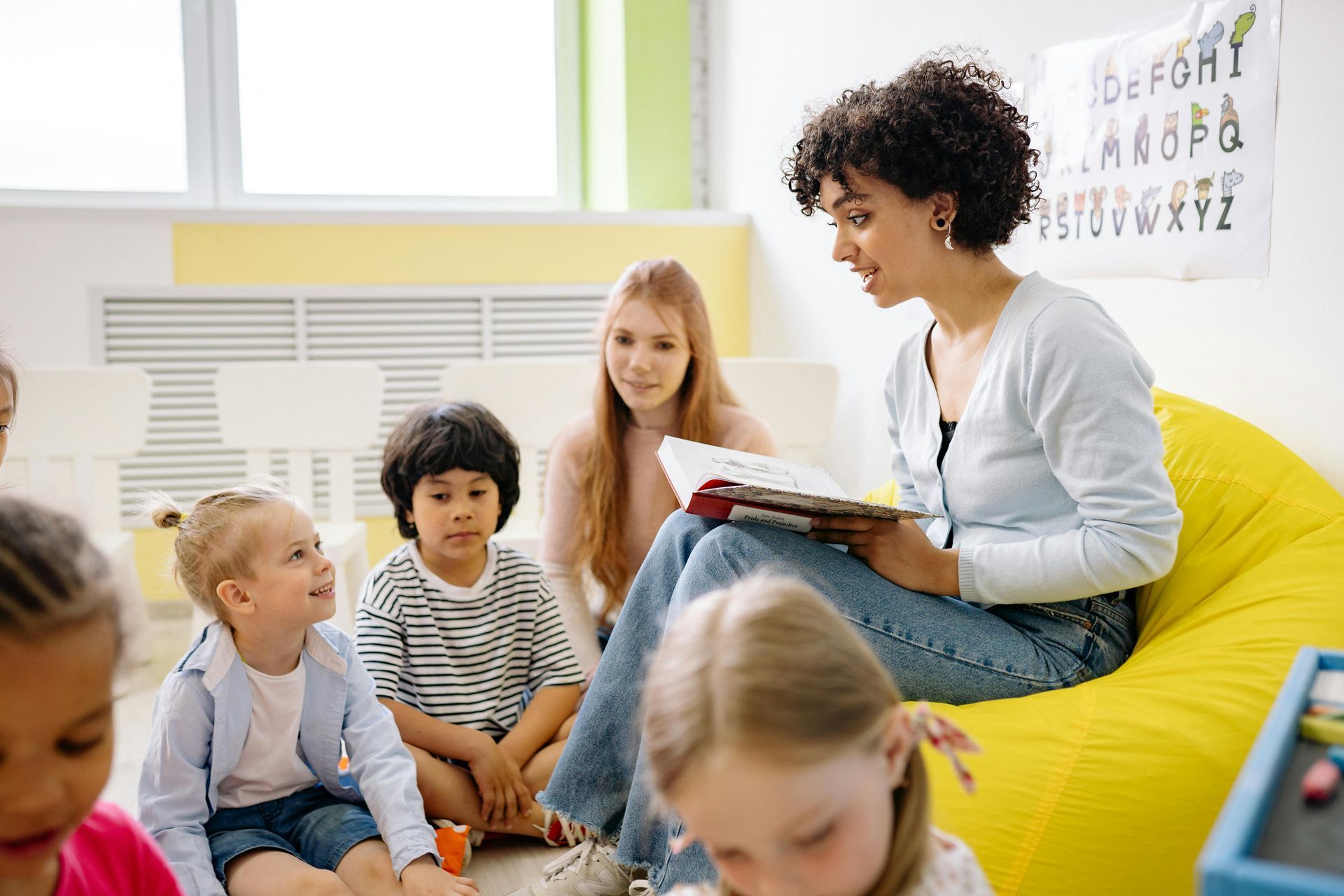 Teacher reading to a group of young students in a classroom during an early literacy session.