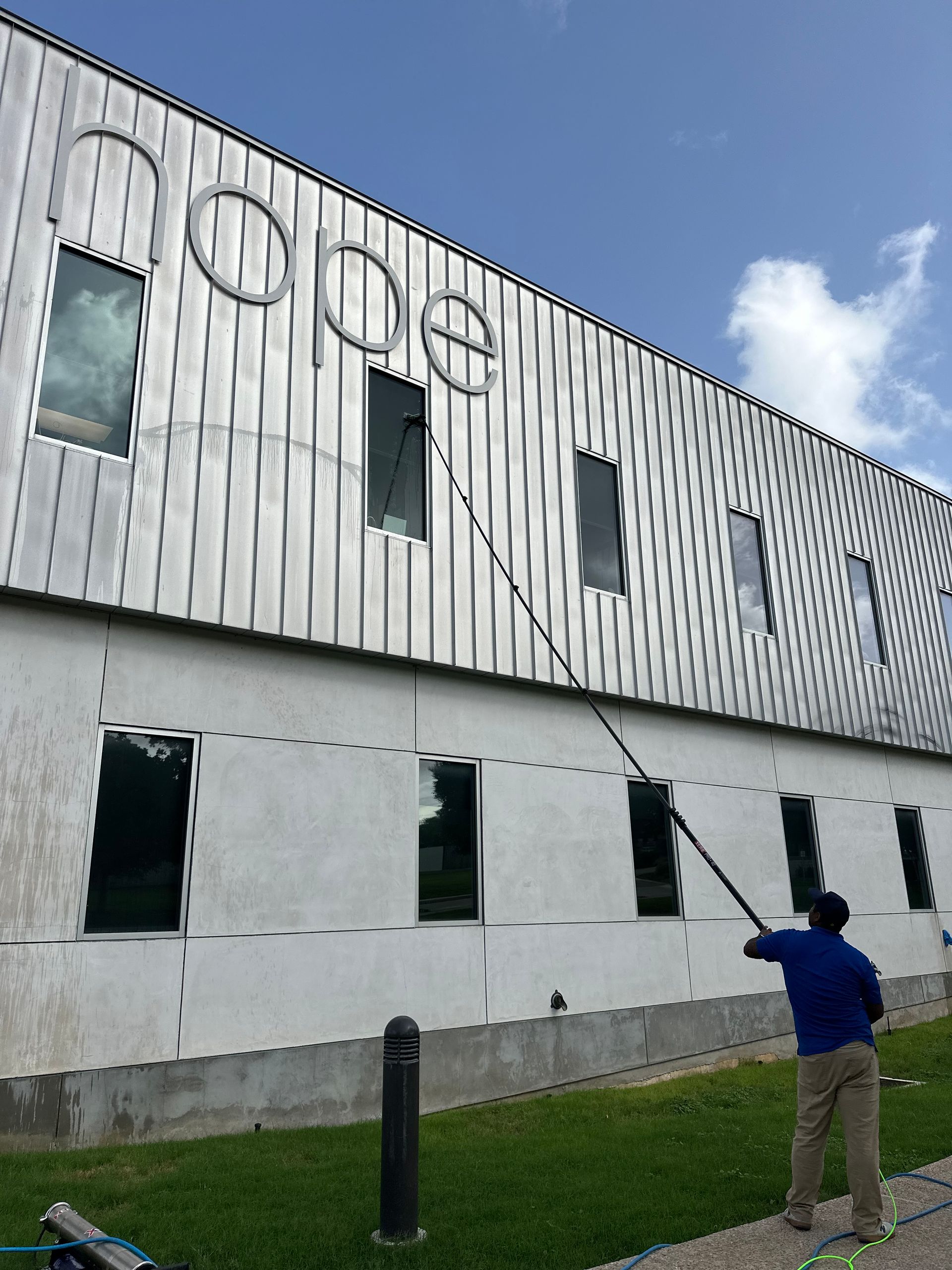 A man is cleaning the side of a building with a hose