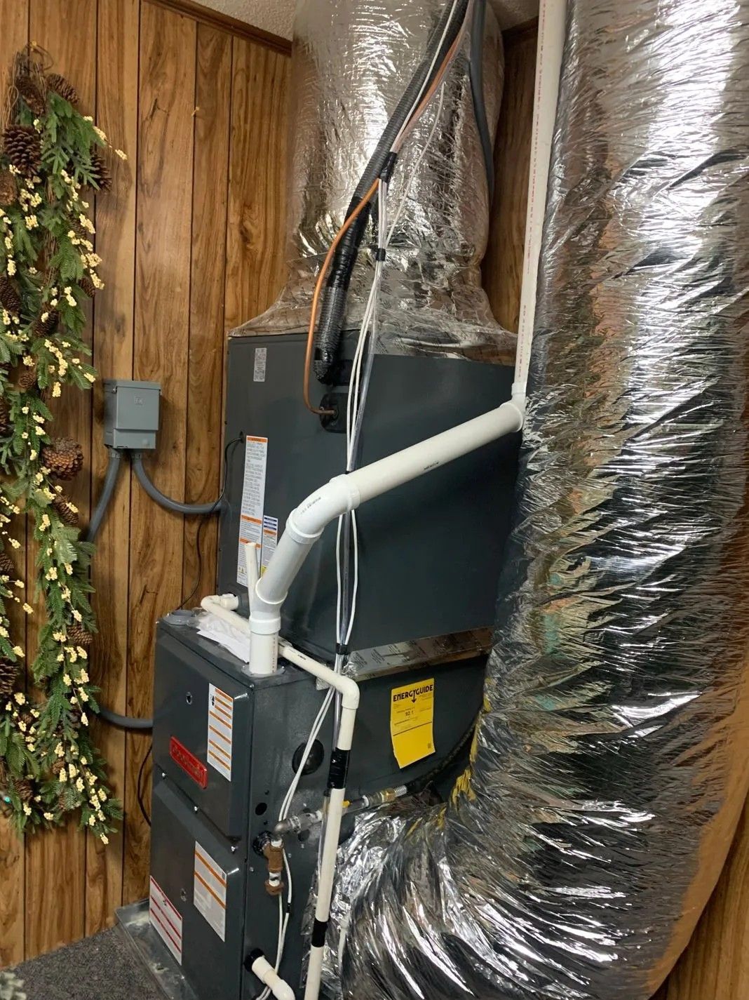 HVAC furnace with silver ductwork and exposed wiring in a utility room