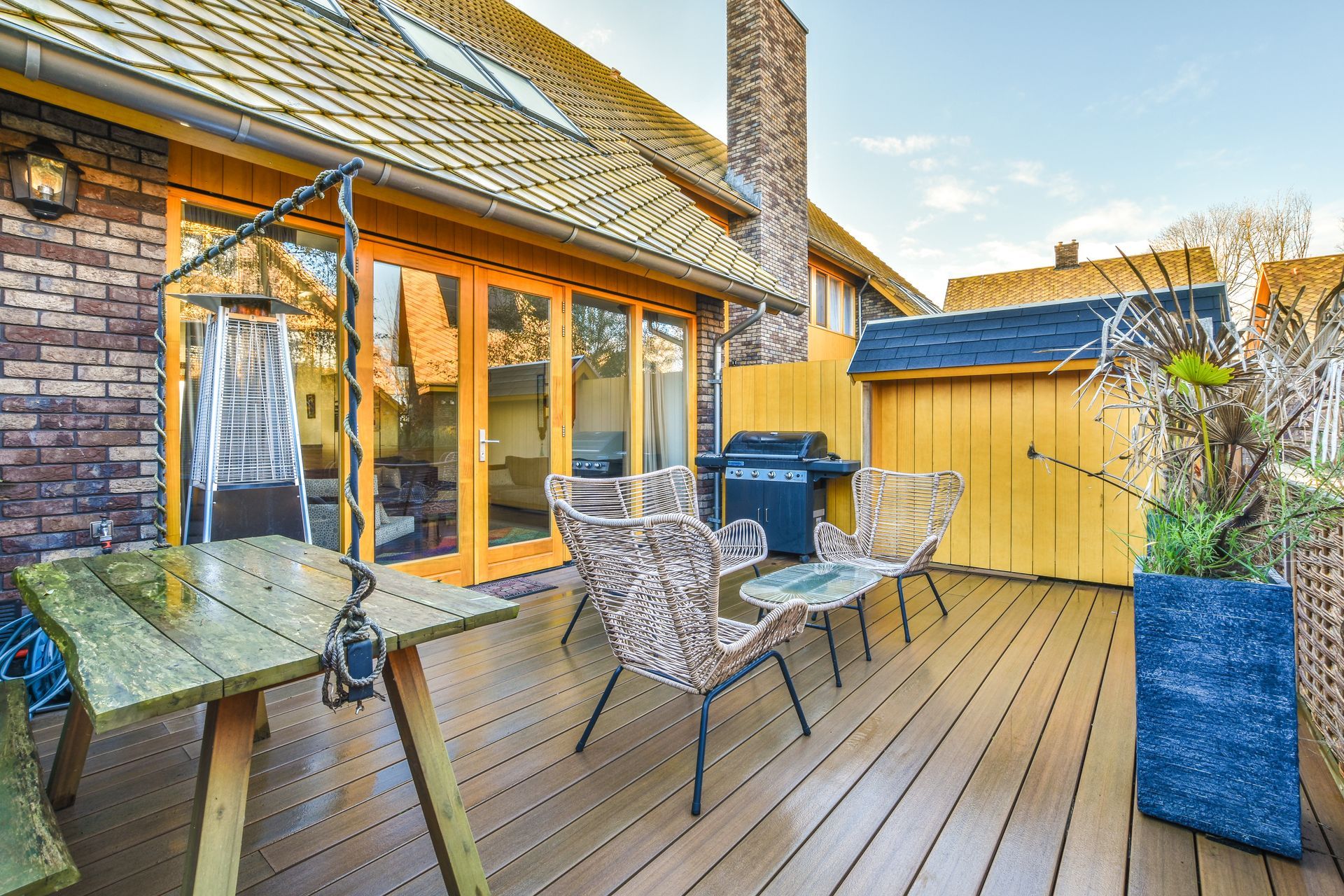 A wooden deck with a table and chairs in front of a house.