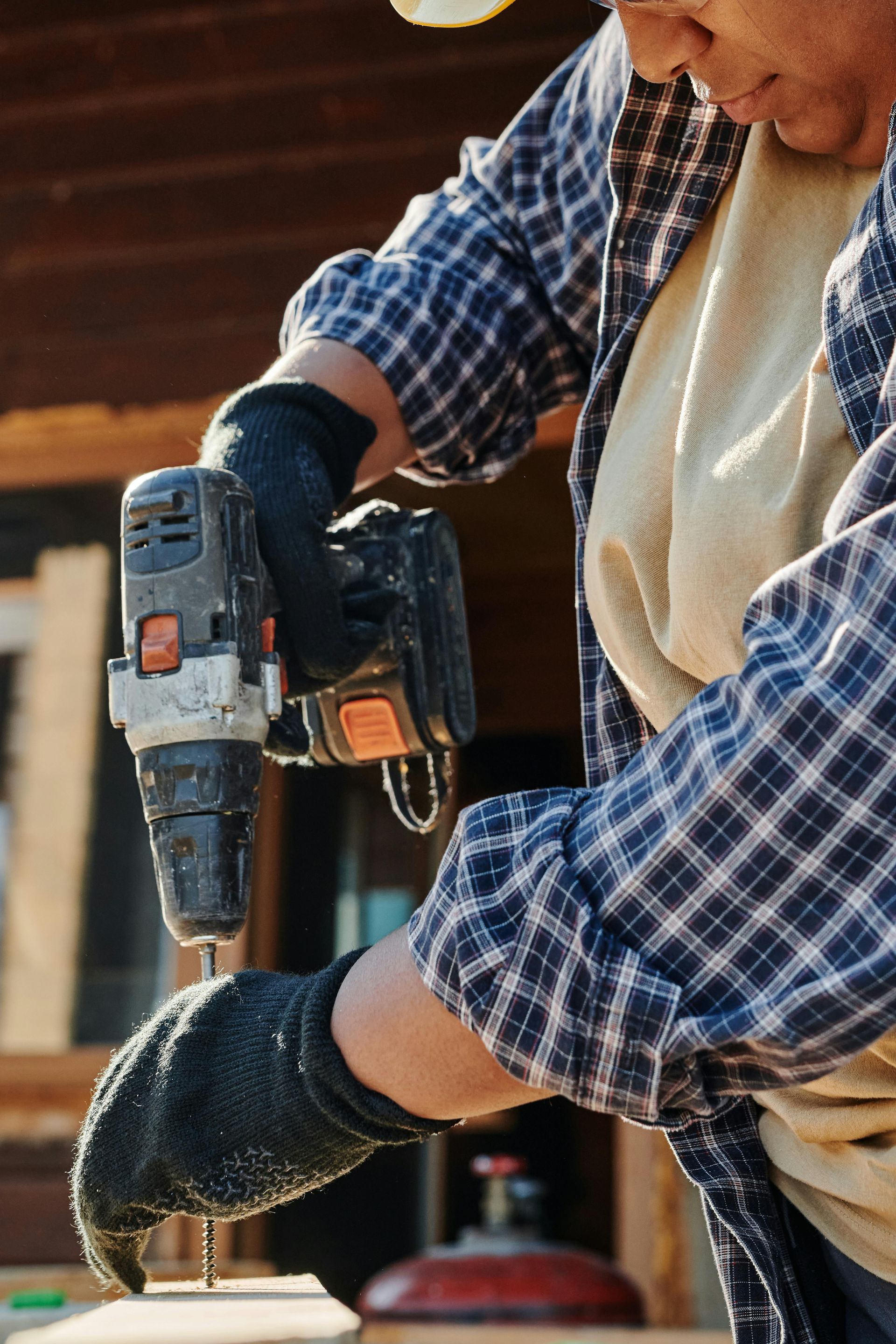 A man is using a drill to drill a hole in a piece of wood.