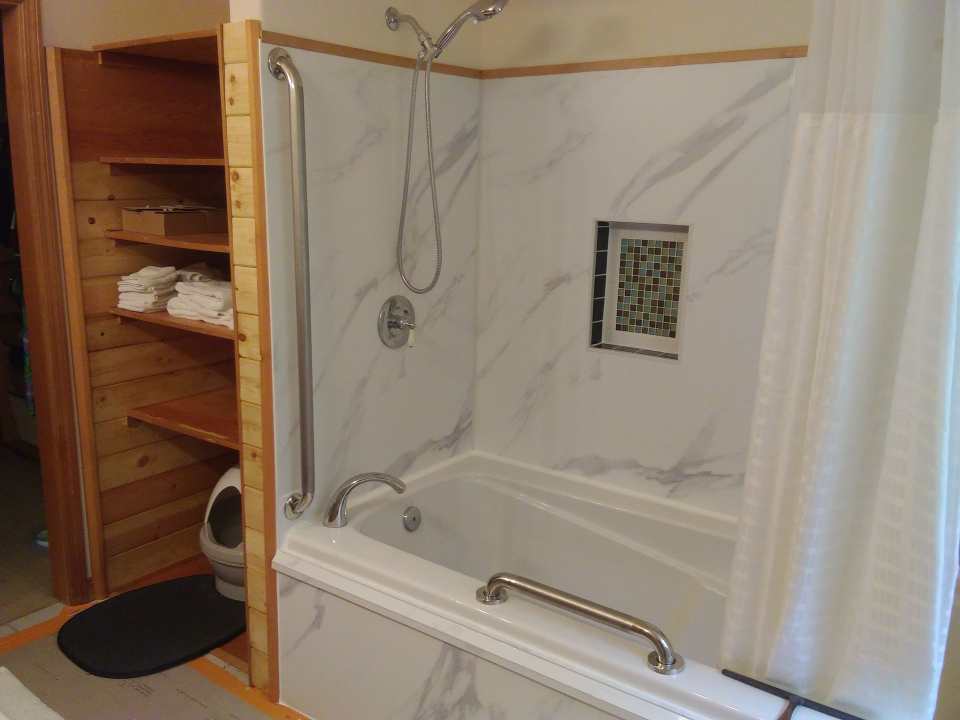 A bathroom with a walk in shower , sink , mirror and tub.