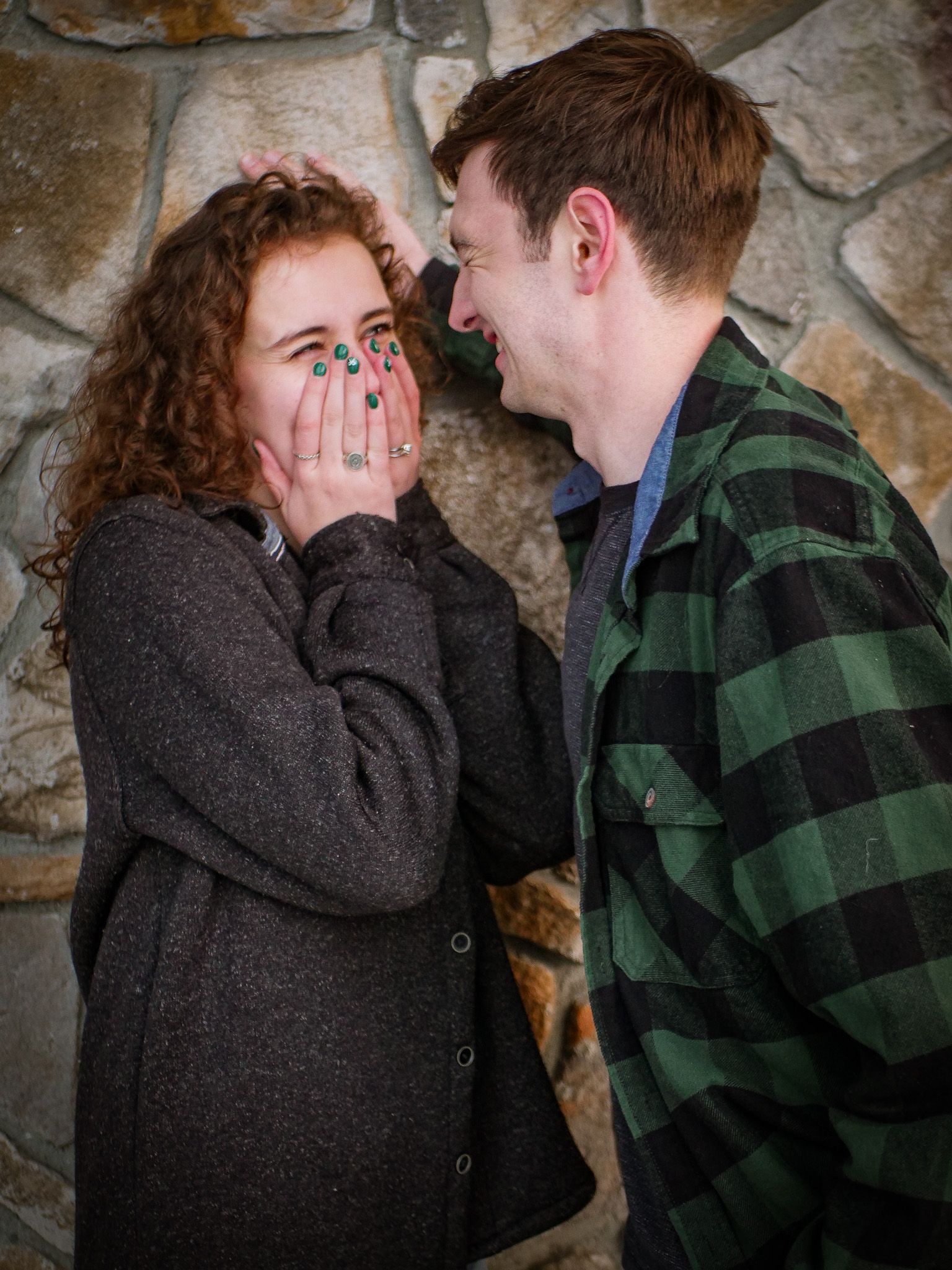 A man and a woman are standing next to each other and the woman is covering her face with her hands.