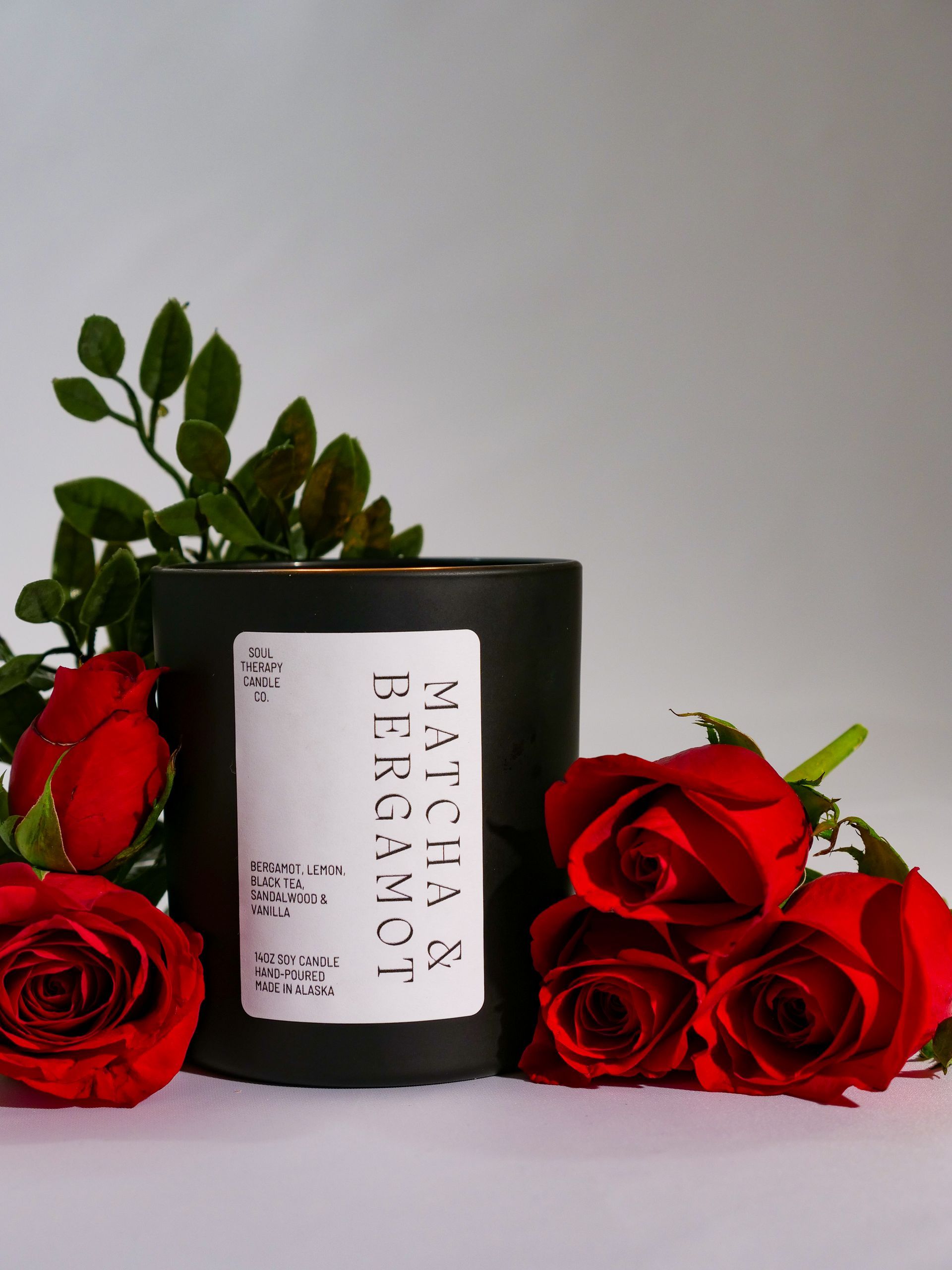A black candle with a label that says matcha and bergamot