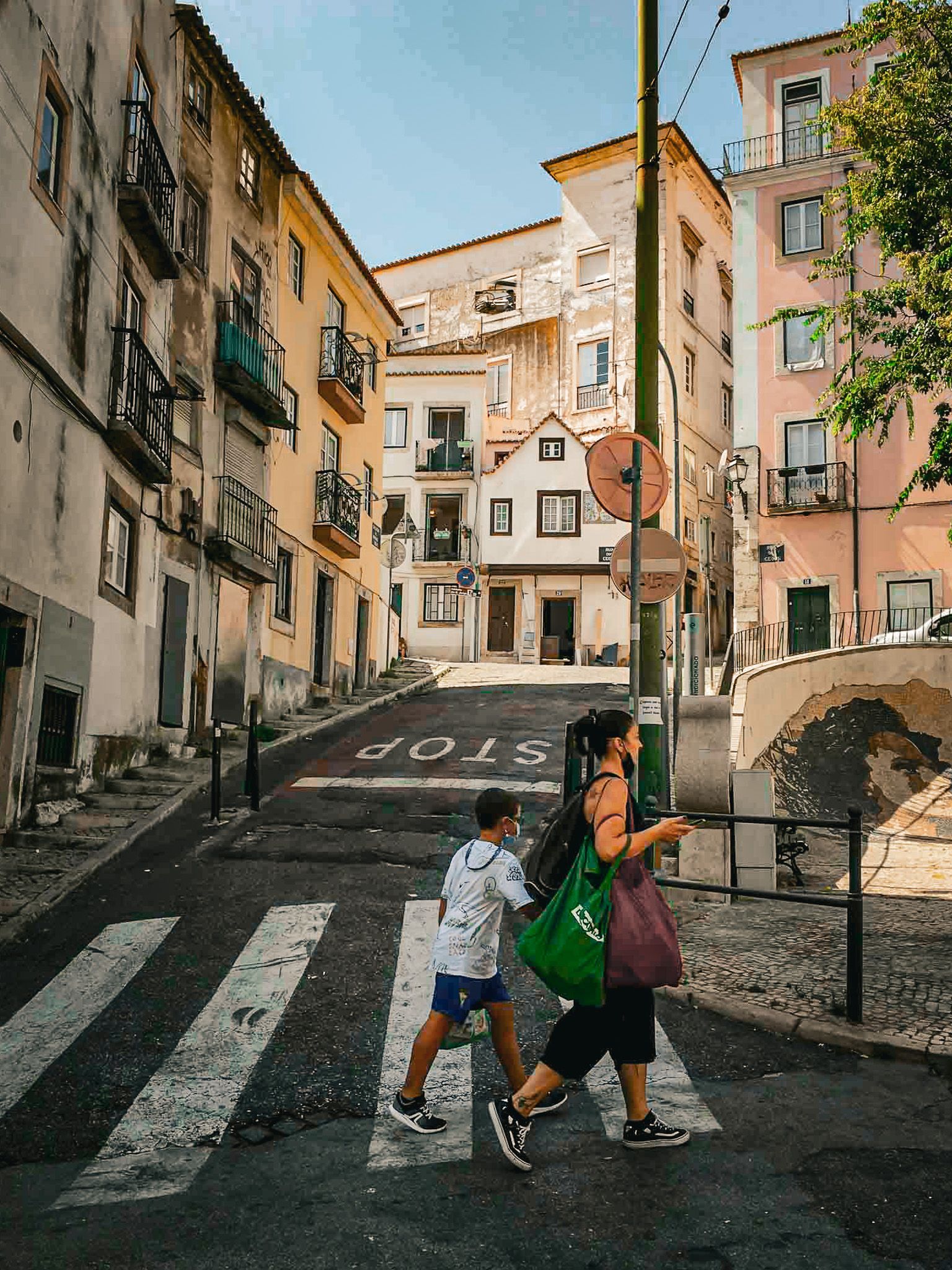 A woman and a child are crossing a street in a city.