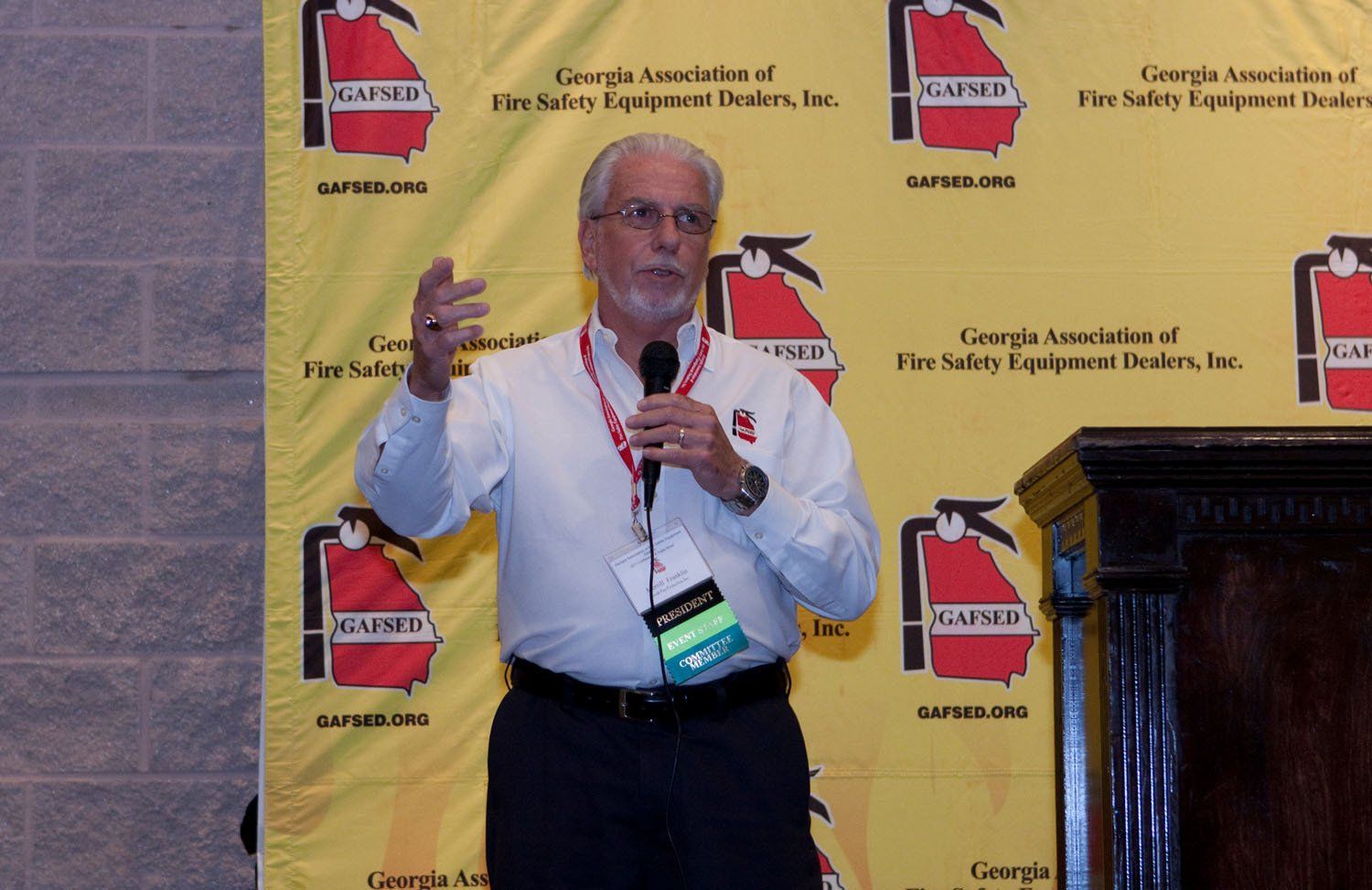 A man stands in front of a yellow backdrop with fire extinguishers on it