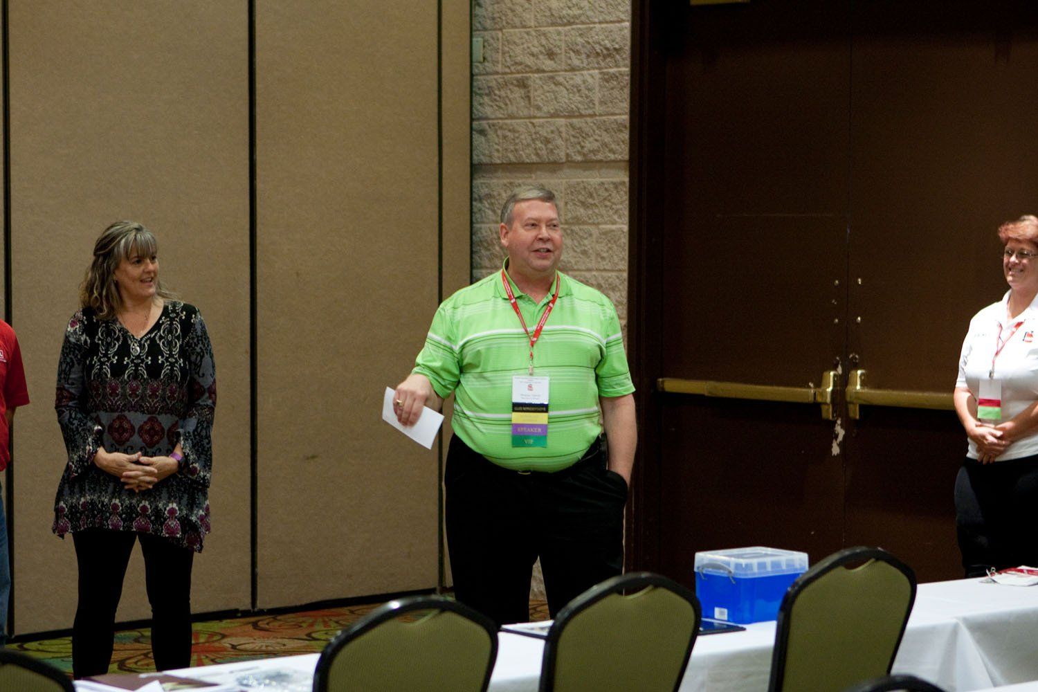 A man in a green shirt stands in front of a group of people