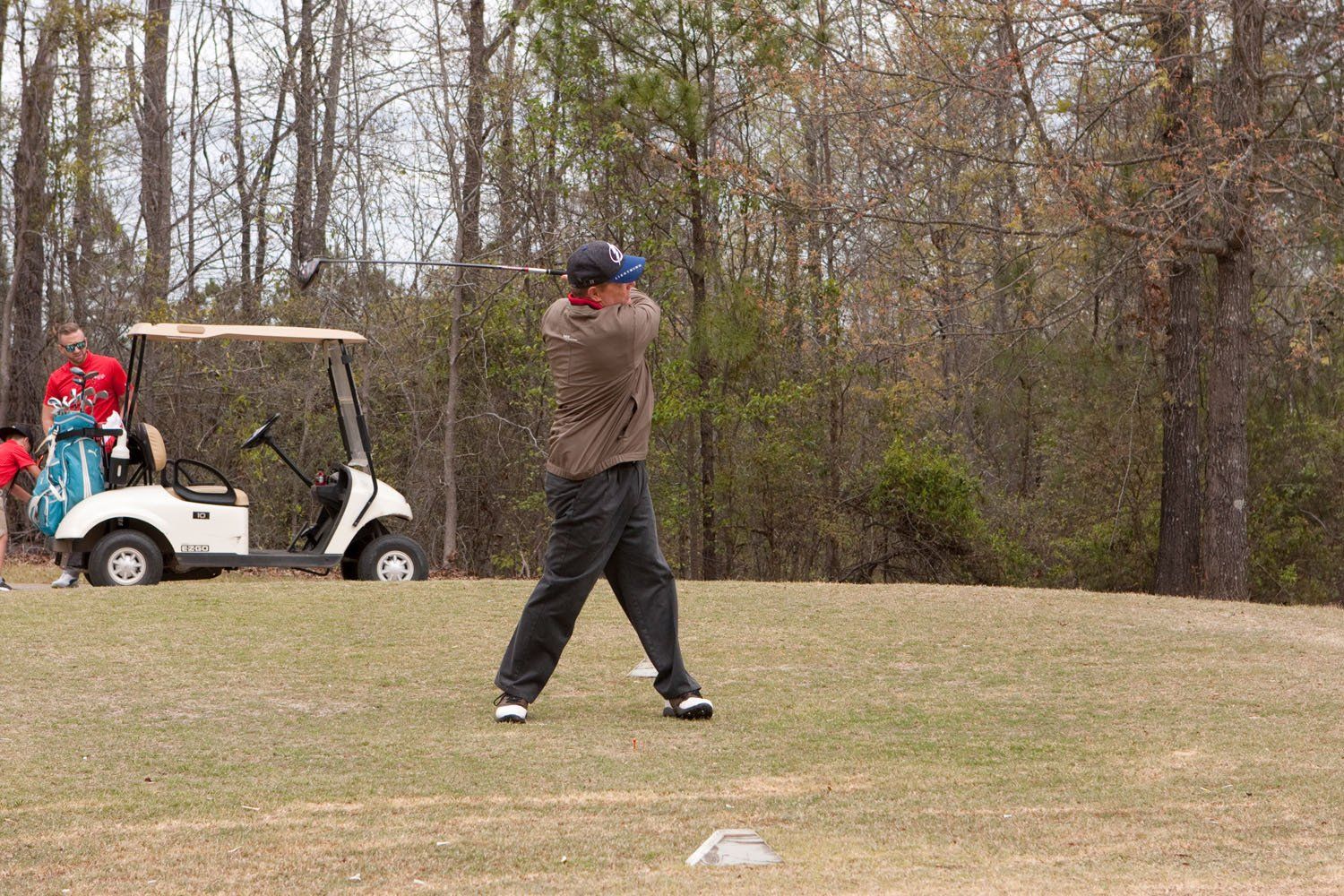 A man is swinging a golf club on a golf course.