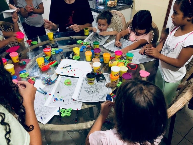 A group of children are sitting around a table playing with play dough