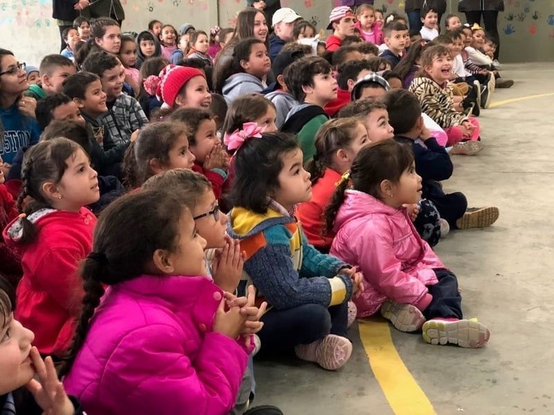 A group of children are sitting on the ground and clapping their hands