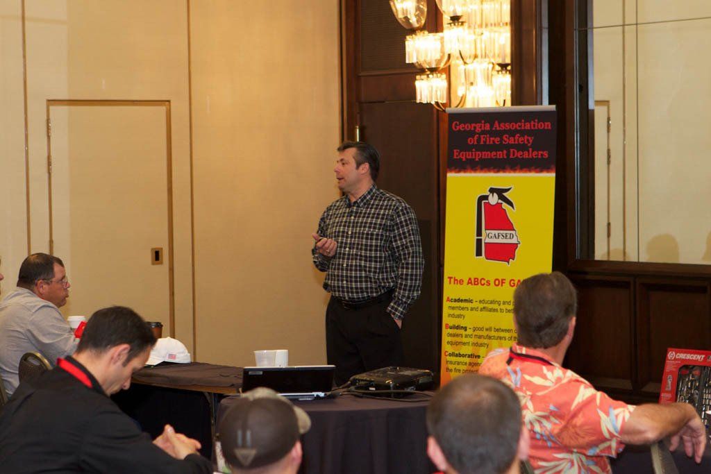A man giving a presentation in front of a sign that says fire safety