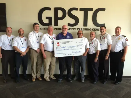 A group of men standing in front of a sign that says gpstc