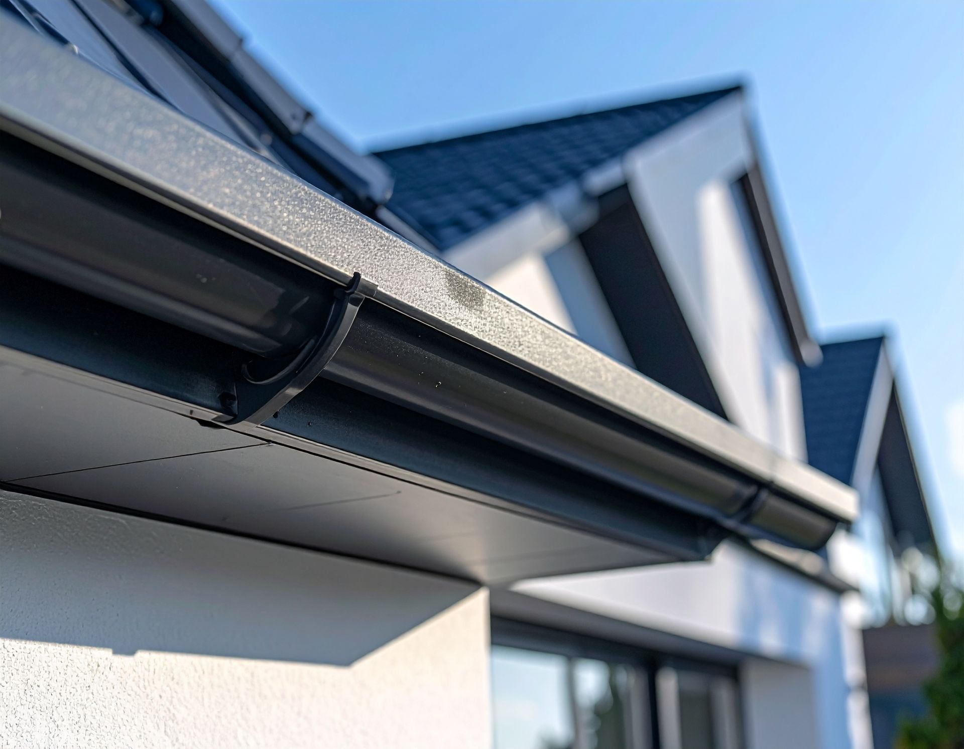 Close-up of a modern house roof gutter and eaves against a blue sky