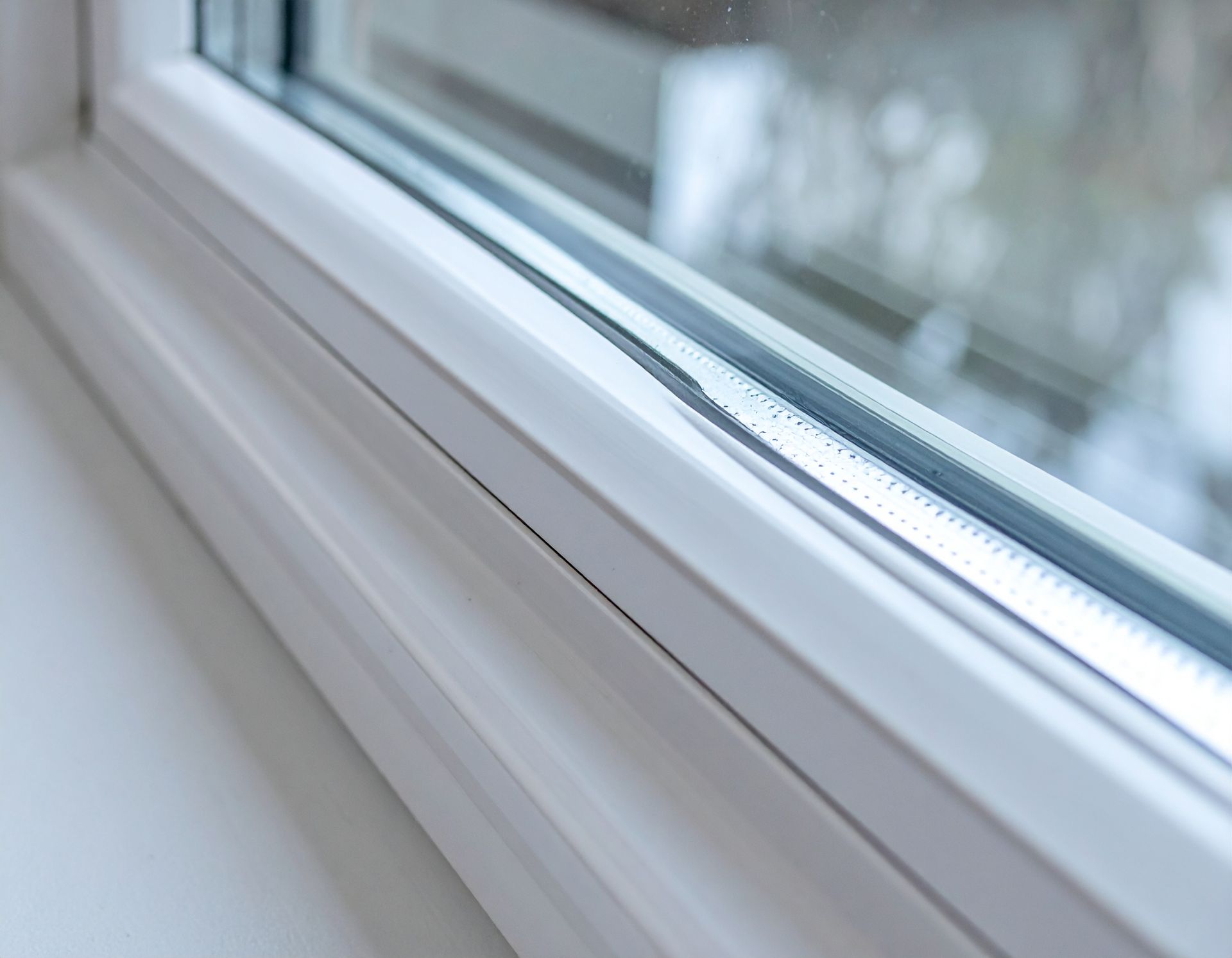 Close-up of a white window frame with sunlight reflecting on the glass and sill
